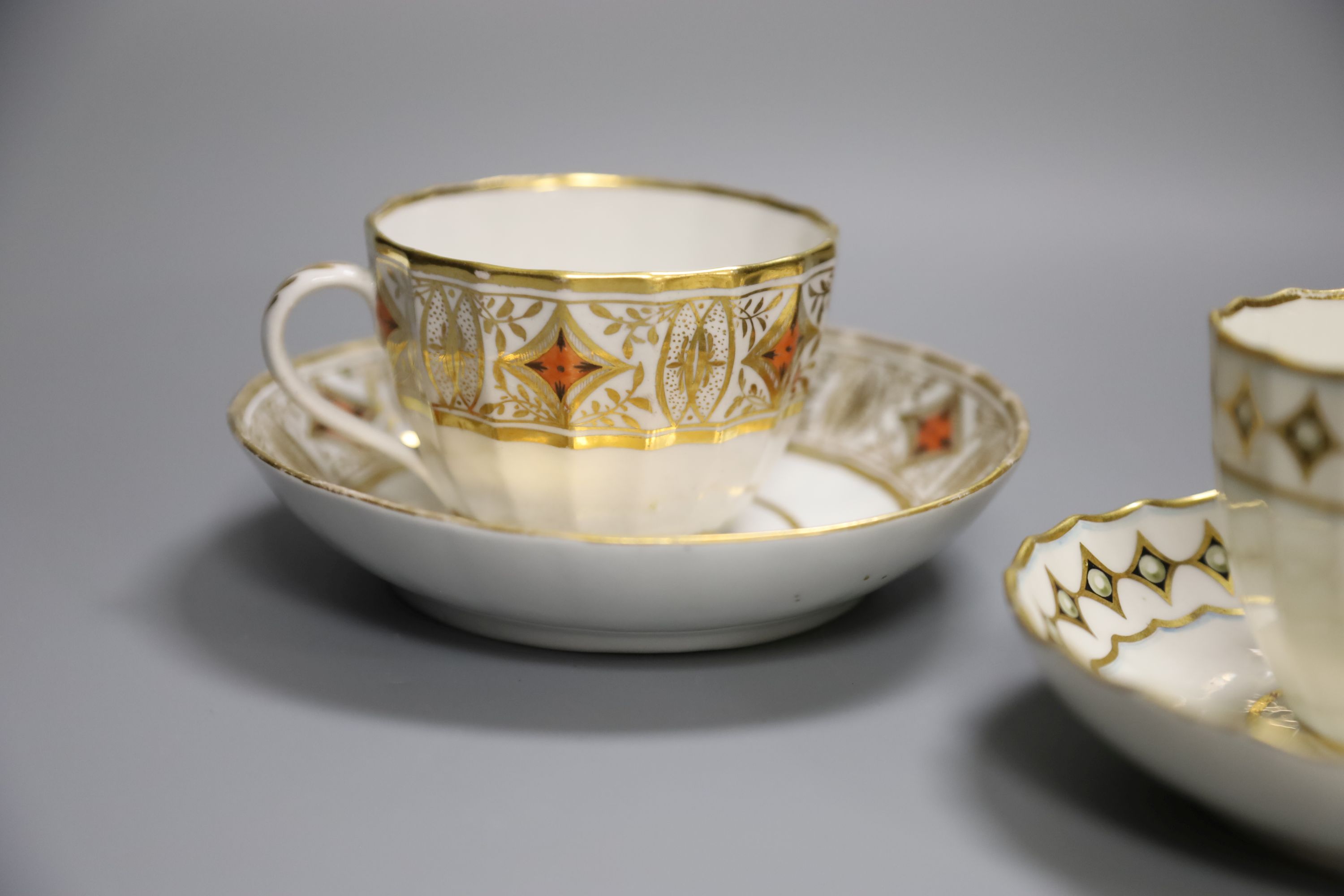 A Derby faceted teacup and saucer painted with pearls on diamond gilding pattern 135 in puce, another similar shaped Derby teacup